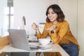 Arab Woman Making Video Call Via Laptop While Eating Breakfast In Kitchen Royalty Free Stock Photo