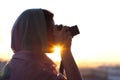 Arab Woman Photographer in a scarf taking picture using Camera on the sunset background. Royalty Free Stock Photo