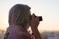 Arab Woman Photographer in a scarf taking picture using Camera on the sunset background. Royalty Free Stock Photo