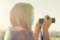 Arab Woman Photographer in a scarf taking picture using Camera on the sunset background. Halal travel concept Royalty Free Stock Photo