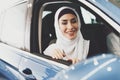 Arab woman sits in new car and looks out of window