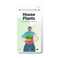 Arab woman taking care of houseplants housewife holding potted plant smartphone screen portrait