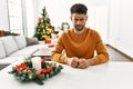 Arab young man sitting on the table by christmas tree skeptic and nervous, frowning upset because of problem