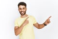 Arab young man standing over isolated background smiling and looking at the camera pointing with two hands and fingers to the side Royalty Free Stock Photo