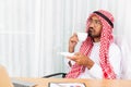 Arabian businessman is thinking about his work and having coffee in his office with computer notebook Royalty Free Stock Photo