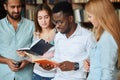 Portrait of young multicultural friends reading books together in the library Royalty Free Stock Photo