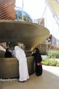 Arabian female receptionist helping a customer on the front desk. Futurist architecture