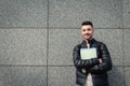 Arabian hipster student standing by stone wall outside. Young smiling man waiting for groupmates Royalty Free Stock Photo