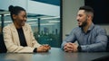 Arabian Indian businessman and African American businesswoman talking at office discuss project business idea sitting at Royalty Free Stock Photo