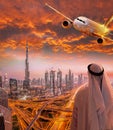 Arabian man with airplane flying over Dubai against colorful sunset in United Arab Emirates Royalty Free Stock Photo