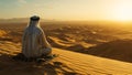 Arabian man meditating in desert at sunset