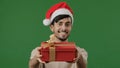 Arabian man in red Santa hat holds gift large red box with gold ribbon wishes new year Christmas celebration friendly Royalty Free Stock Photo