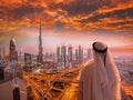 Arabian man watching cityscape of Dubai with modern futuristic architecture in United Arab Emirates.