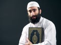 Arabian muslim man with beard holding the holy book Quran
