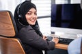 Arabian or Muslim woman works in a call center operator and customer service agent wearing microphone headsets working on computer Royalty Free Stock Photo