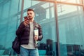 Arabian student using smartphone outside. Serious guy looks at phone in front of modern building after classes Royalty Free Stock Photo