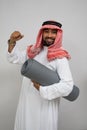 an arabian turban smiling excitedly while holding a roll of mattress and the other hand clenched up