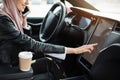 Arabian woman sitting in car and using electronic dashboard