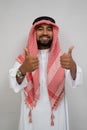 an arabian young man in a turban smiling while standing looking at the camera with thumbs up while talking