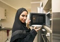 Arabian young woman in kitchen using microwave oven Royalty Free Stock Photo