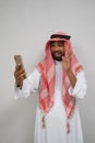 an arabian youth in a turban makes a video call using a mobile phone while smiling with a hand gesture