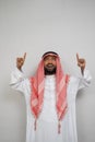 an arabian youth in a turban standing looking up with a hand gesture pointing up