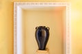Arabic antique vase on a pedestal as an element of decor in hotel. A large black amphora with two handles in a niche in the yellow Royalty Free Stock Photo