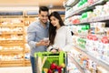 Arabic Couple Using Phone Shopping Groceries Buying Food In Supermarket Royalty Free Stock Photo