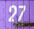 Arabic figure 27 twenty seven painted with white on an old wooden wall covered with violet paint