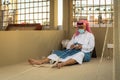 Arabic fisherman, repairing home-made fishing net and wooden yacht, wearing face mask and sits on the floor of traditional boam Royalty Free Stock Photo