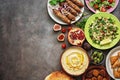 Arabic and Middle Eastern dinner table. Hummus, tabbouleh salad, Fattoush salad, pita, meat kebab, falafel, baklava, pomegranate.