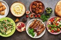 Arabic and Middle Eastern dinner table. Hummus, tabbouleh salad, Fattoush salad, pita, meat kebab, falafel, baklava, pomegranate.