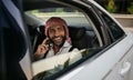 Arabic Muslim businessman looking out car window on mobile phone wearing Keffiyeh Royalty Free Stock Photo