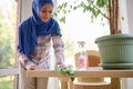 Middle aged woman with covered head in hijab doing chores at home. Housekeeping concept. Arabic Muslim woman concentrated on