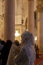 An Arabic Muslim woman wearing floral traditional head wrap is praying
