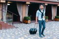 Young Guy Arab Businessman Student Came go to Restaurant With Suitcase in Hand, Smiling at Camera, Stops and Looks Away. Royalty Free Stock Photo