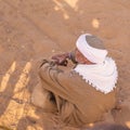 Arab traditional dressed man siting in desert and looking towards Pyramids in Cairo Egypt Royalty Free Stock Photo