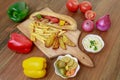 Arabic Shish Tawook Sandwich with bell pepper, onion, tomato, dip, hummus, veggies and fires isolated on wooden board side view Royalty Free Stock Photo