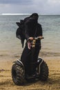 An arabic woman is riding a segway on a beach