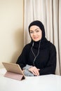 Arabic woman using tablet pc computer. Southeast Asian student at home. Muslim teenage girl living lifestyle.