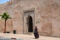 Arabic woman walking near an old arch on a big wall in Meknes, Morocco