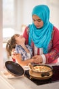 Arabic young woman with little kid in kitchen