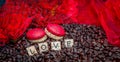 Red macaroon on rosted coffee beans sexy background with red flowers and letters LOVE