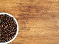 Arabica coffee beans in white bowl with copy space on wooden background