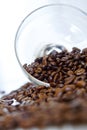 Arabica roasted coffee beans spill out of a transparent glass bowl. Light background. Daylight. Vertical image Royalty Free Stock Photo