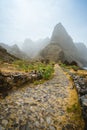 Aranhas mountain peak in the valley with house ruins and stony hiking path going up the mountain from Ponta do Sol to