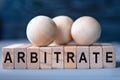 ARBITRATE - word on wooden blocks on dark blue background Royalty Free Stock Photo