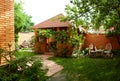 Arbor of red brick near the house. Wicker chairs and table Royalty Free Stock Photo