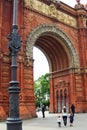 Arc de Triomf with big street lights and family walking into the arc.