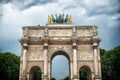 Arc de triomphe du carrousel in paris, france. Arch monument and green trees on cloudy sky. Architectural symbol of peace victory Royalty Free Stock Photo